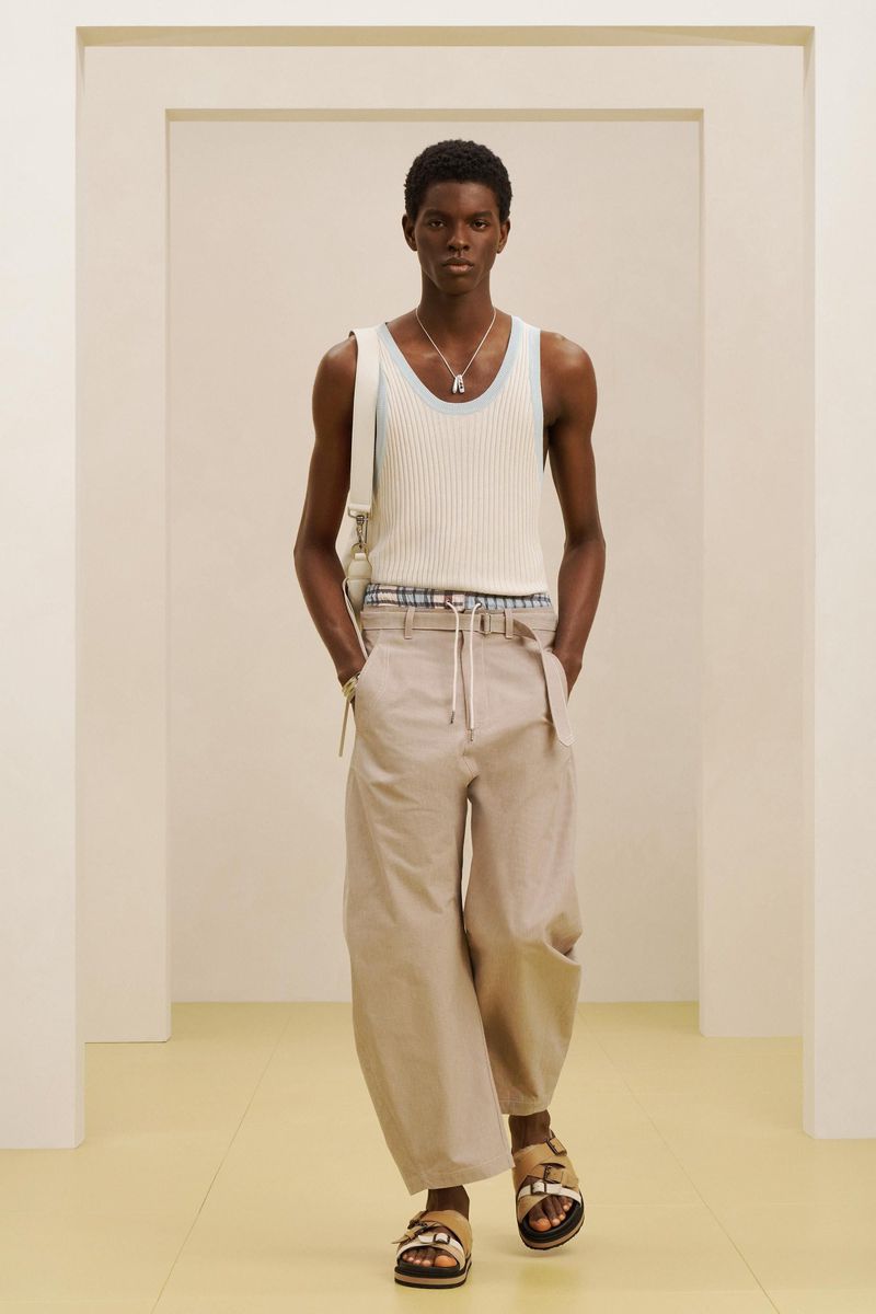 Model wearing a white ribbed tank top and beige trousers standing inside a minimal studio setting for Zara SRPLS