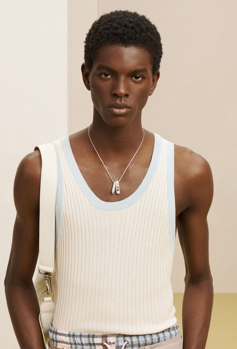 Close-up portrait of a Black man wearing a white ribbed tank top with pale blue trim and a silver pendant necklace for Zara SRPLS.