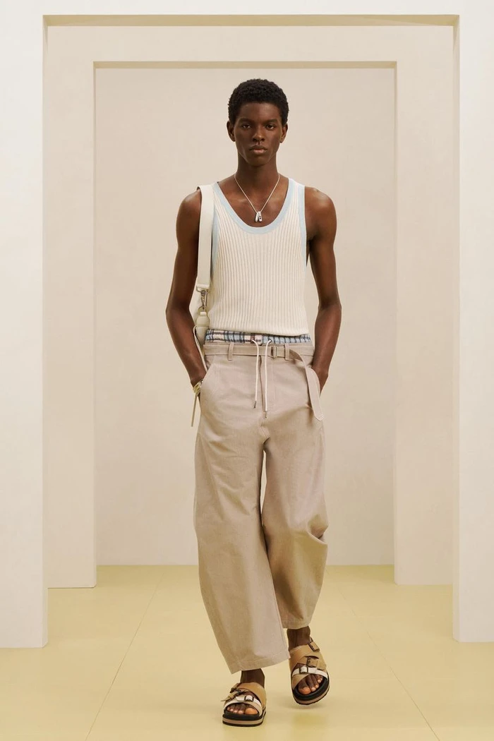 Model wearing a white ribbed tank top and beige trousers standing inside a minimal studio setting for Zara SRPLS