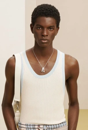 Close-up portrait of a Black man wearing a white ribbed tank top with pale blue trim and a silver pendant necklace for Zara SRPLS.
