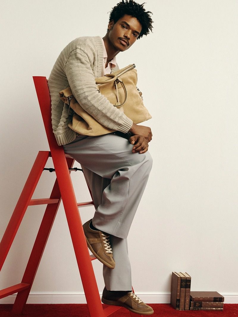Model Nile Winchester seated on a red ladder holding a beige bag for The Webster project The Everyday Elevated by Johnson Lui.