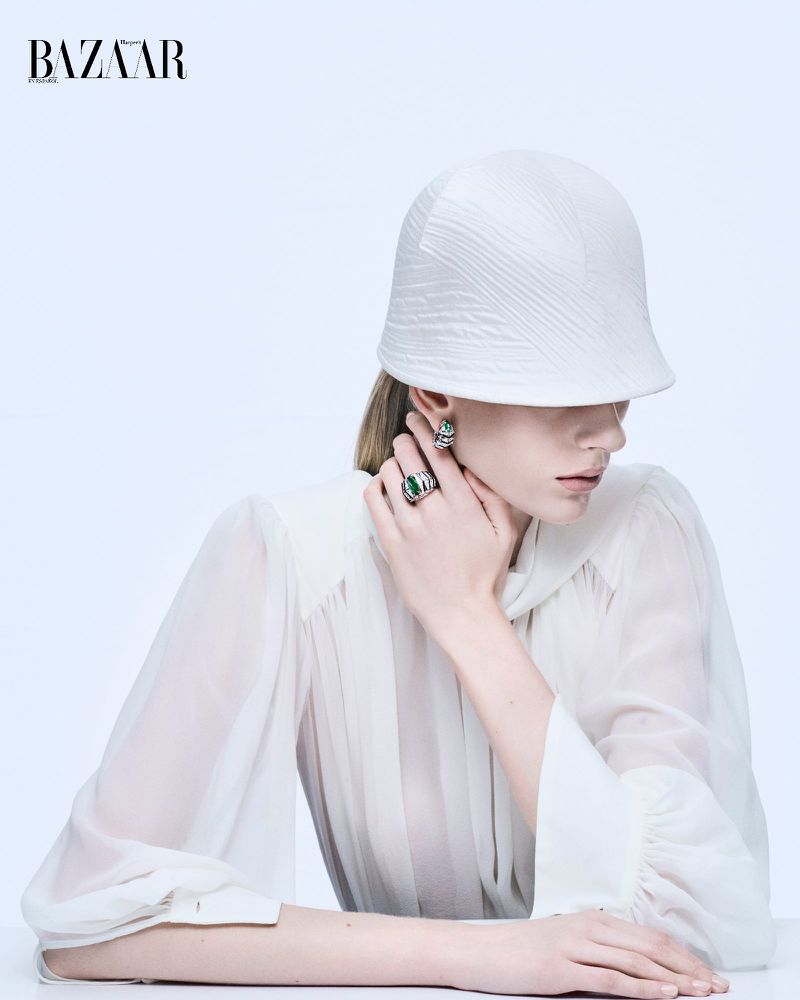 Model wearing a white bucket hat and sheer white blouse against a seamless white background, featured in Harper's Bazaar Mexico.