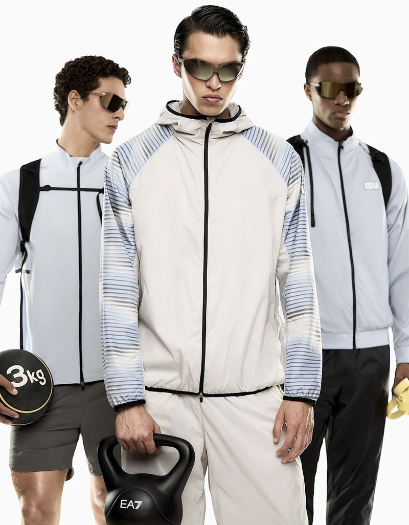 Three male models in athletic wear and sunglasses holding kettlebells against a white seamless background for Emporio Armani