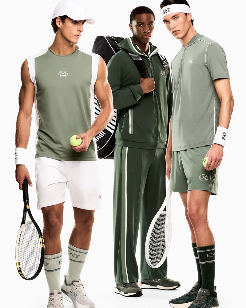 Three male models in Emporio Armani sportswear posing with tennis equipment against a white studio background.