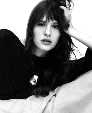 Model in black top with sculptural silver pendant and rings against white background for Adolfo Dominguez SS 26