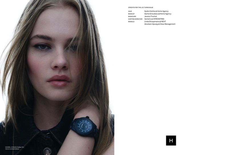 Close-up shot of a young adult female model wearing a dark denim jacket and a watch, gazing directly at the camera with a neutral expression.