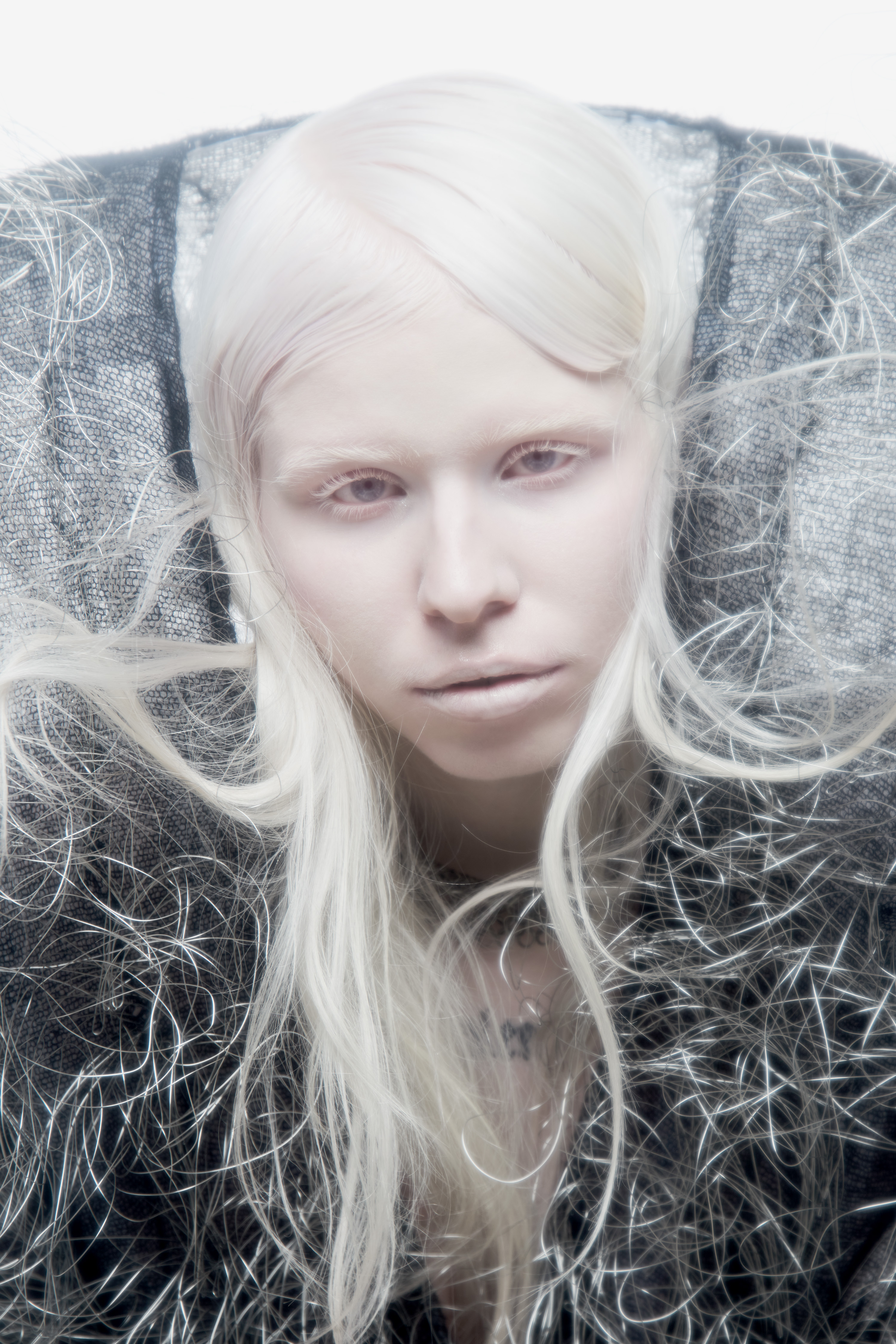 Close-up portrait of a pale model with white hair and textured dark metallic collar for Flanelle Magazine