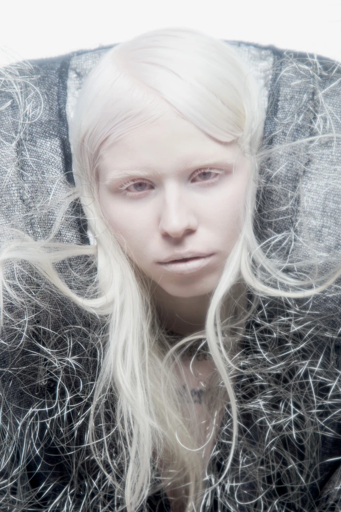 Close-up portrait of a pale model with white hair and textured dark metallic collar for Flanelle Magazine