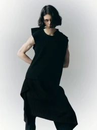 Model with dark hair wearing a black sleeveless top against a plain light grey background