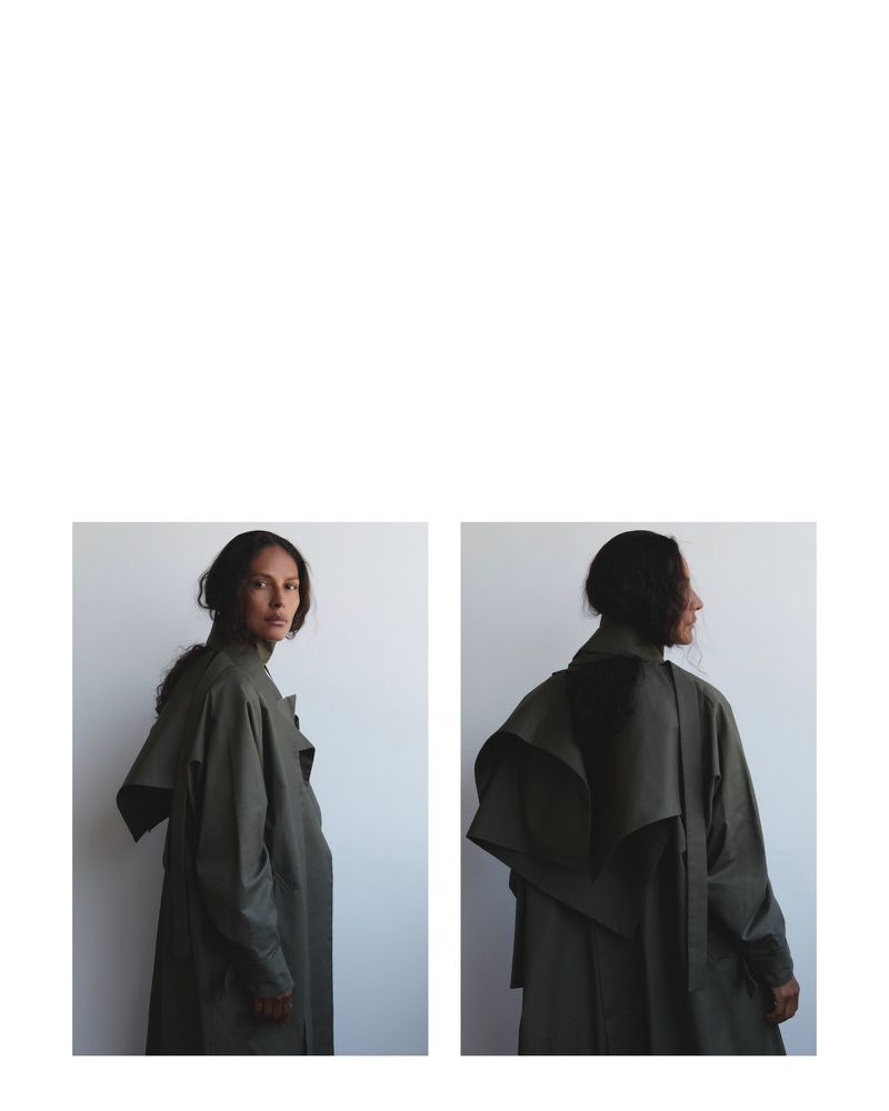 Studio shot of a woman in a green trench coat, from both front and back. Minimalist fashion, soft lighting, clean aesthetic.