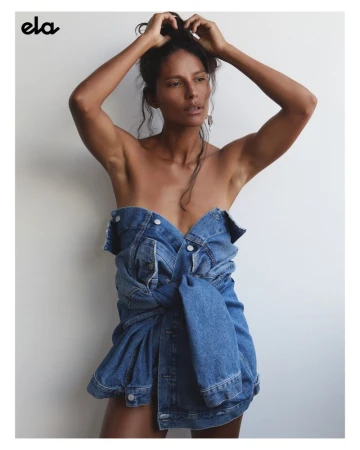 Portrait of a dark-haired woman wearing a denim jacket, shot in a photo studio against a neutral background with soft lighting.