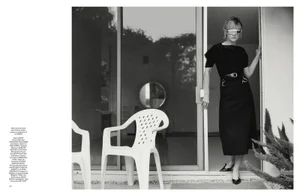 Carey Mulligan standing in a doorway wearing dark futuristic eyewear and a black outfit, photographed in monochrome.