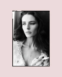 Black and white portrait of a woman wearing a white lace garment holding a cigarette, framed with a pink border.