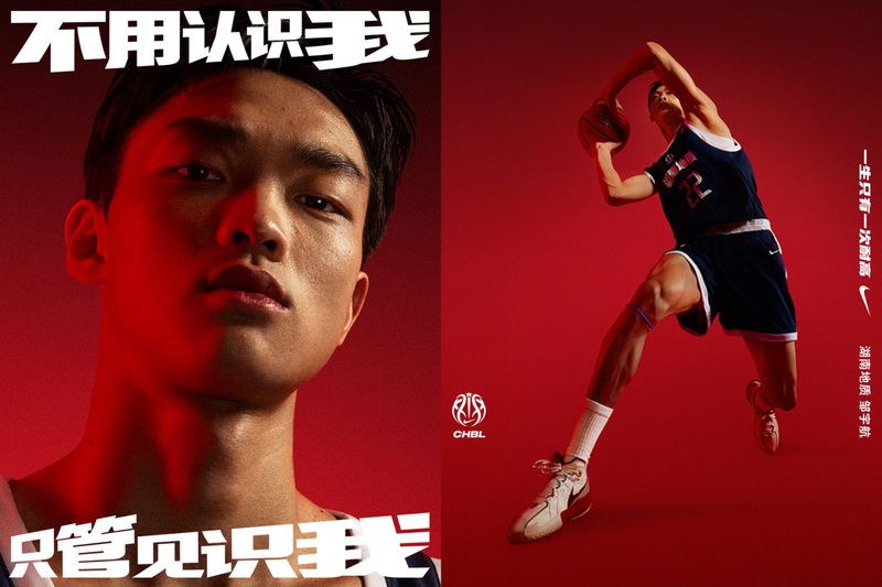 Basketball player in blue jersey and white shorts leaping with a basketball against a vibrant red backdrop in a Nike campaign shot.