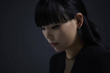 Portrait of Dami Im with dark hair and fringe wearing a black top and earrings for L'Oreal Paris True Match