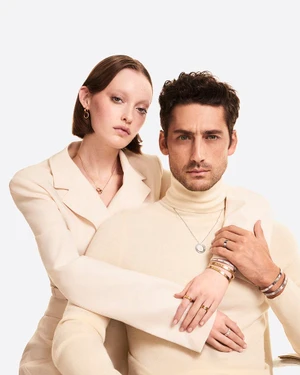 Man and woman wearing cream turtleneck and blazer with jewelry against a plain white background for Cartier Santos de Cartier project