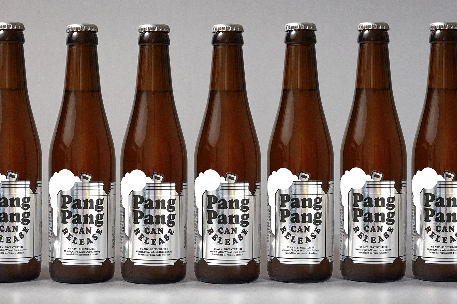 Seven brown glass beer bottles with silver and black labels arranged in a row against a light grey background.