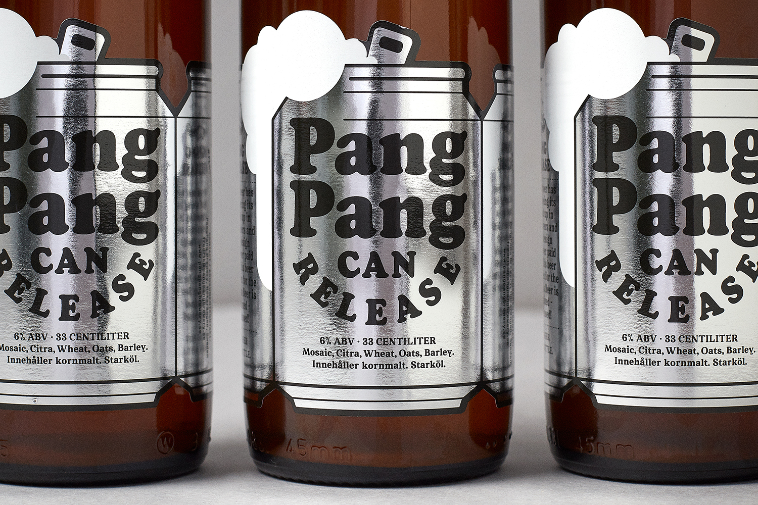Close-up product shot of PangPang Brewery beer bottles featuring metallic silver labels with bold black typography.