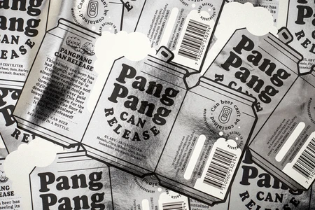 Close-up overhead monochrome packaging design featuring PangPang Brewery beer can labels with bold typography and metallic texture.