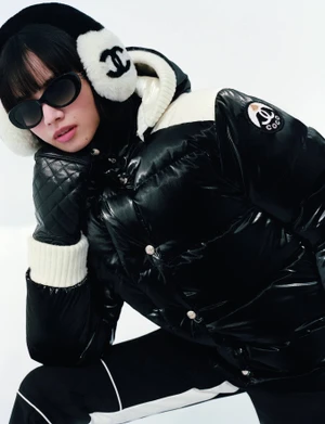 Model Nana Komatsu wearing a black and white Chanel puffer jacket, earmuffs, and sunglasses against a white background