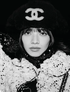 Close-up black and white portrait of model Nana Komatsu wearing a fuzzy winter hat with Chanel logo and textured jacket