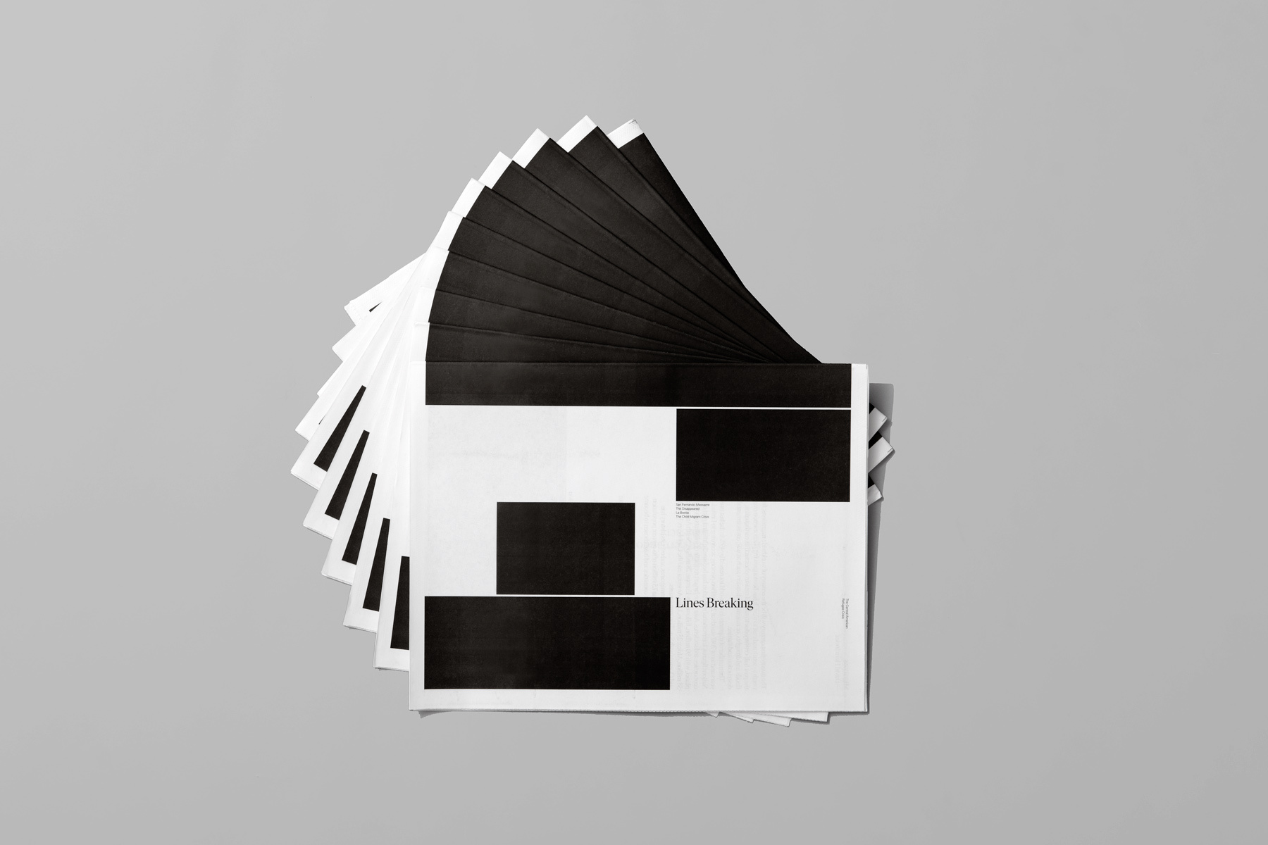 A fan of black and white printed paper sheets arranged in a circular overlapping stack on a neutral grey background