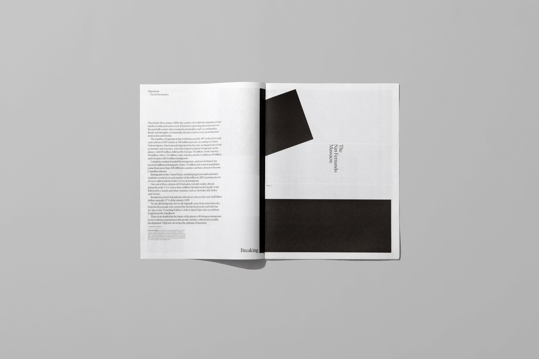 Open magazine spread on grey surface showing typography and black geometric abstract shapes.
