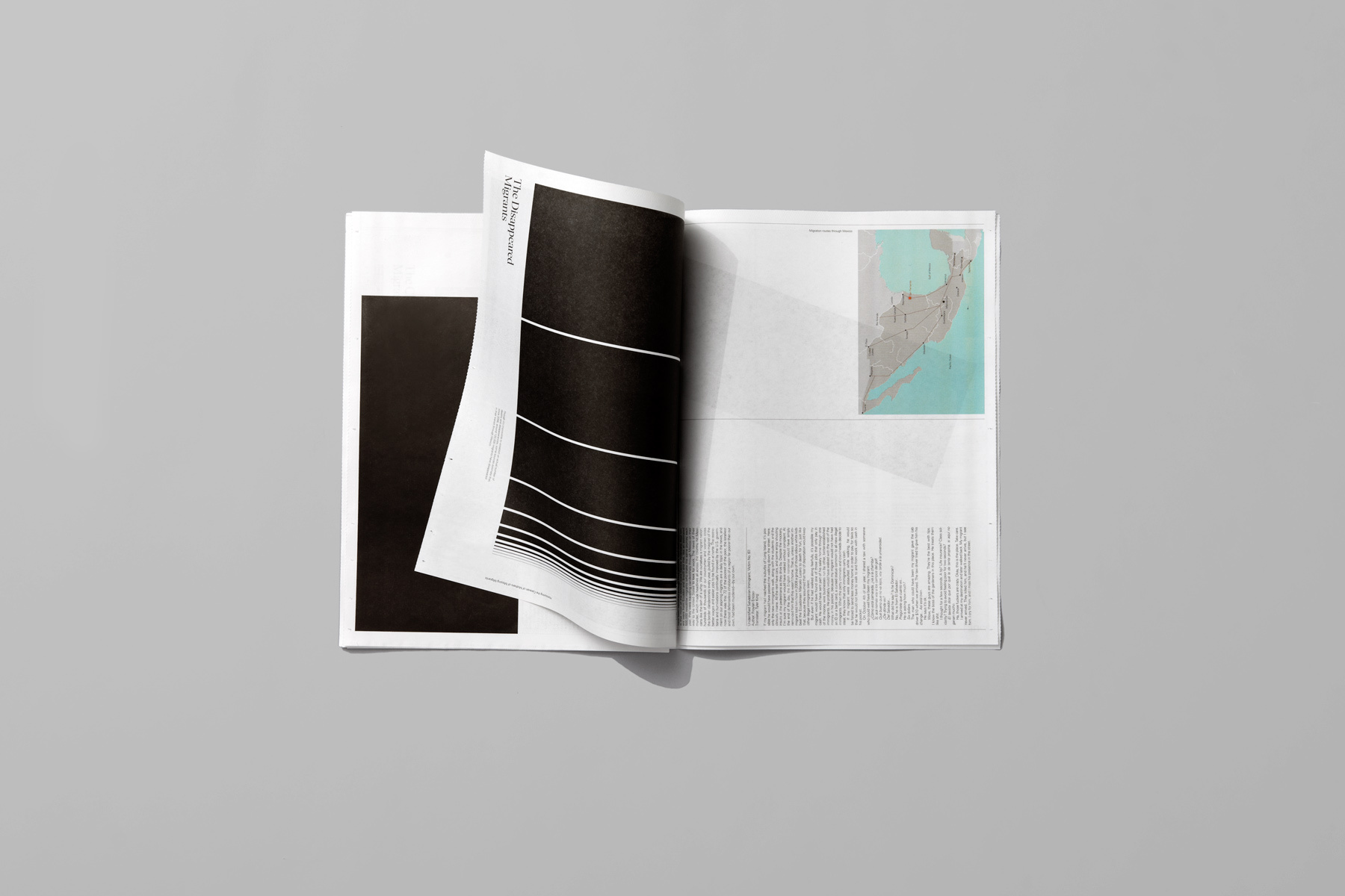 An open graphic publication with a curled page showing abstract black-and-white graphic lines, set against a plain grey backdrop.