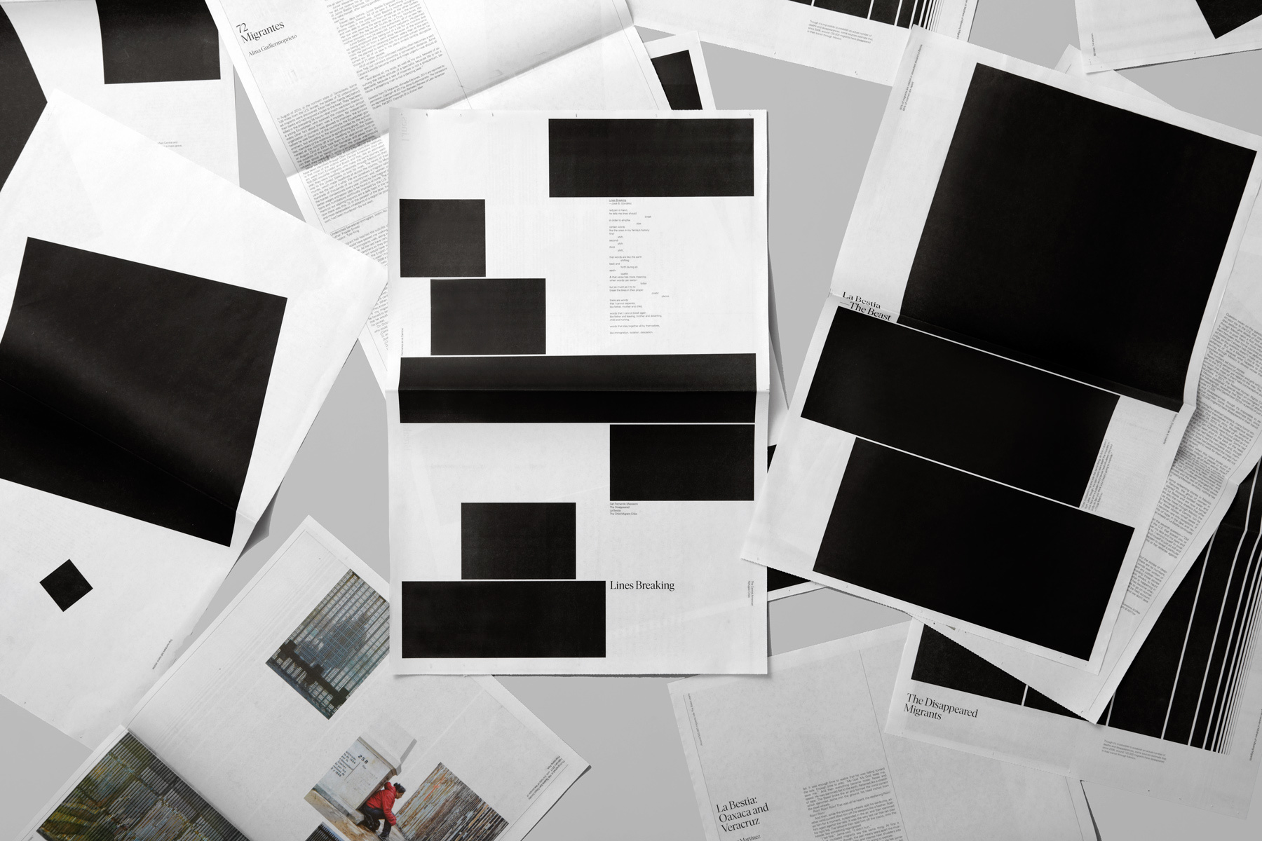 Overhead view of scattered black and white printed pages featuring bold black rectangular blocks and typography.