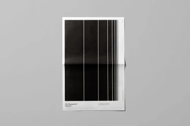 A black and white poster with vertical lines and text resting on a plain grey surface.