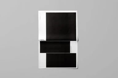 Minimalist graphic design layout with stark black rectangular blocks on white paper against a plain grey backdrop.