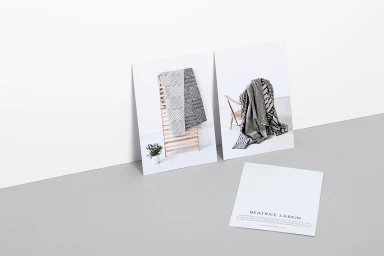 Three printed cards displaying black and white geometric patterned textiles leaning on a grey surface against a white wall.