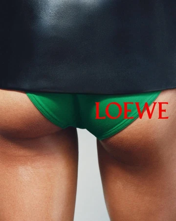 Close-up rear view of a person wearing green briefs and a dark top with the LOEWE logo overlaid in red.