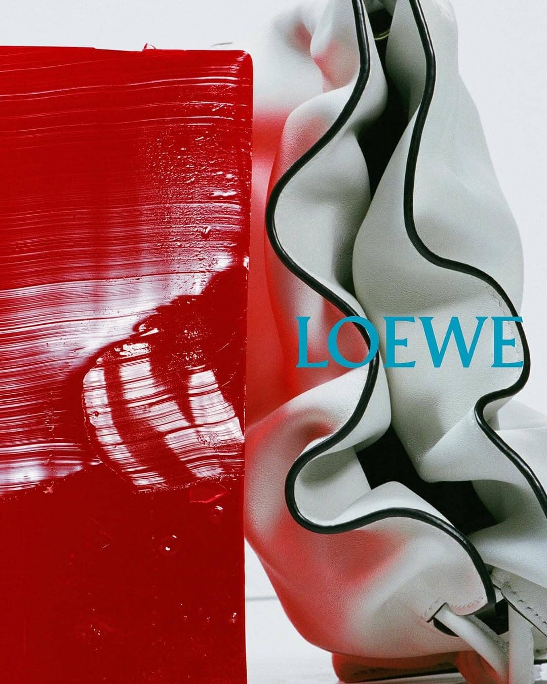 Loewe leather handbag next to a textured red block against a white background