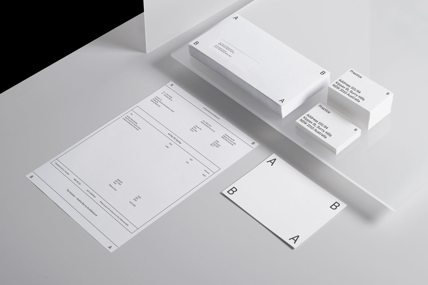 Minimalist stationery set featuring white letterhead, envelopes, and business cards arranged on an angled neutral surface.