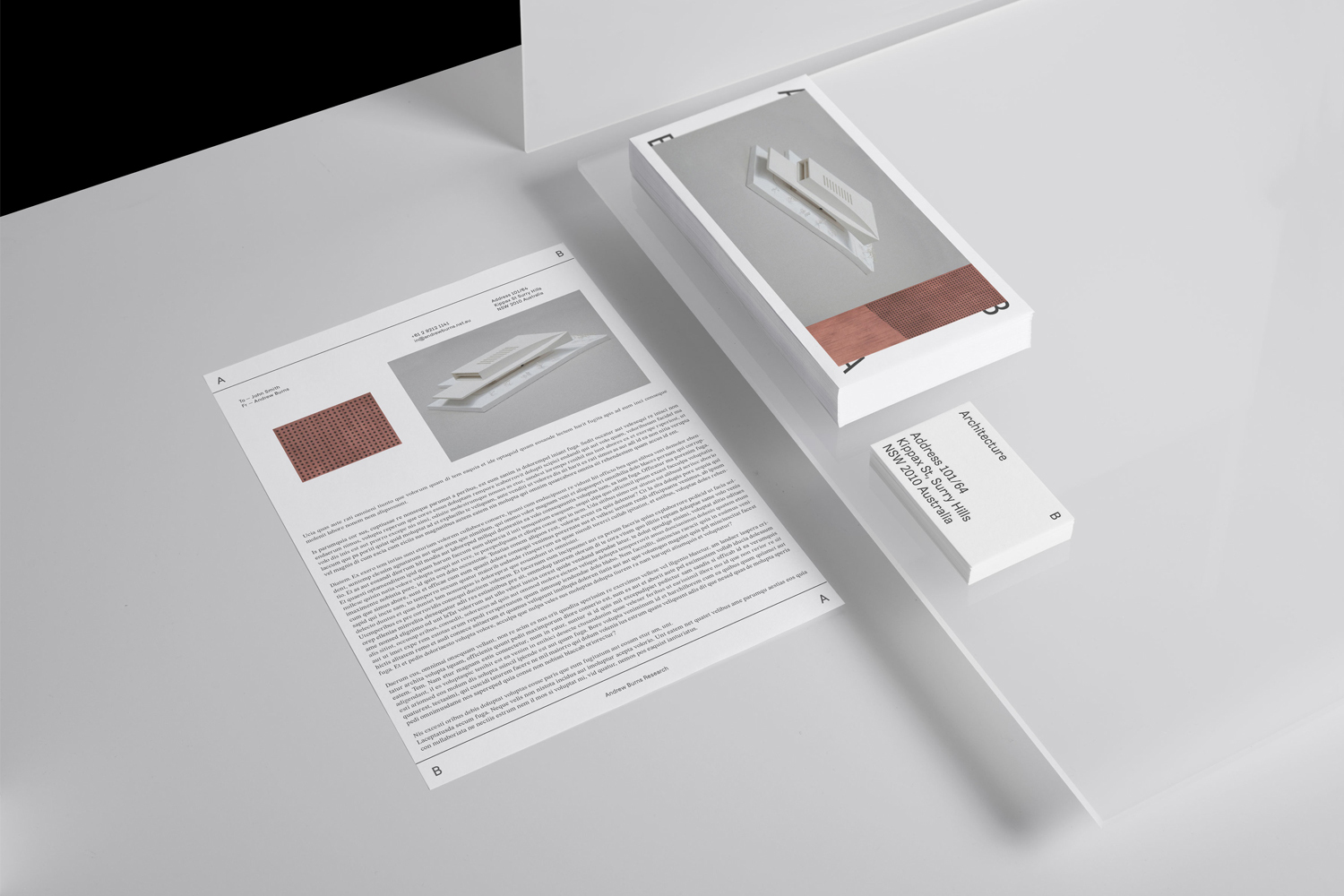 Minimalist architectural branding layout featuring letterhead, business card, and stacked stationery on a clean grey background.