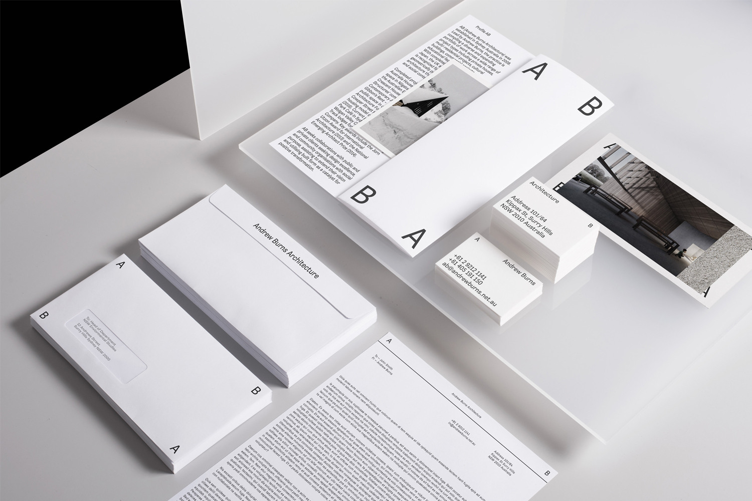 Minimalist brand identity stationery set with white envelopes, letterhead, and business cards on a clean surface.