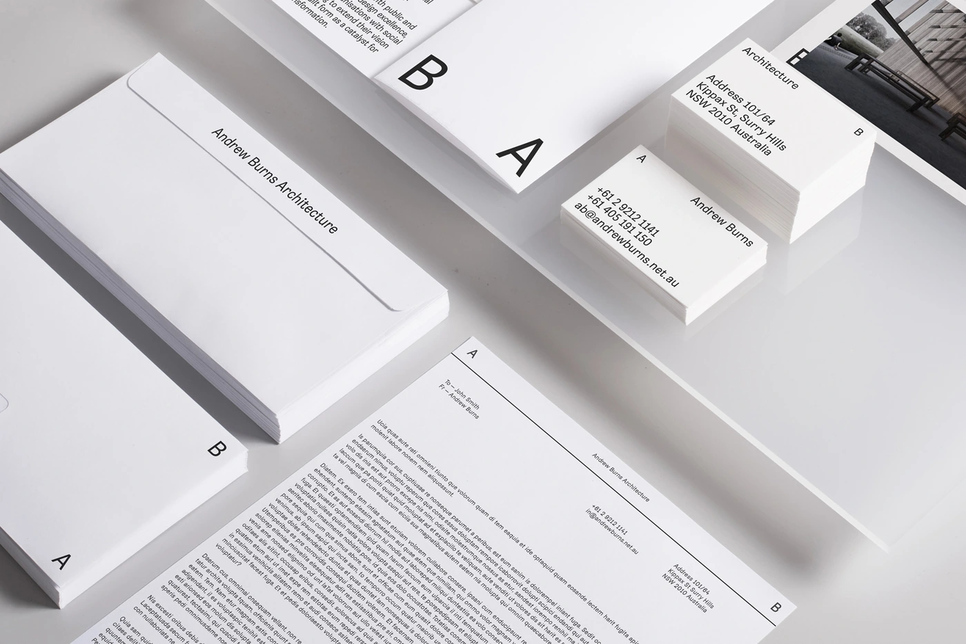 Minimalist stationery set featuring white business cards, letterheads, and envelopes with clean typography for Andrew Burns Architecture.