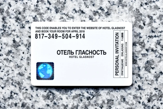 White invitation card with black typography and a blue globe icon resting on a grey granite textured surface.