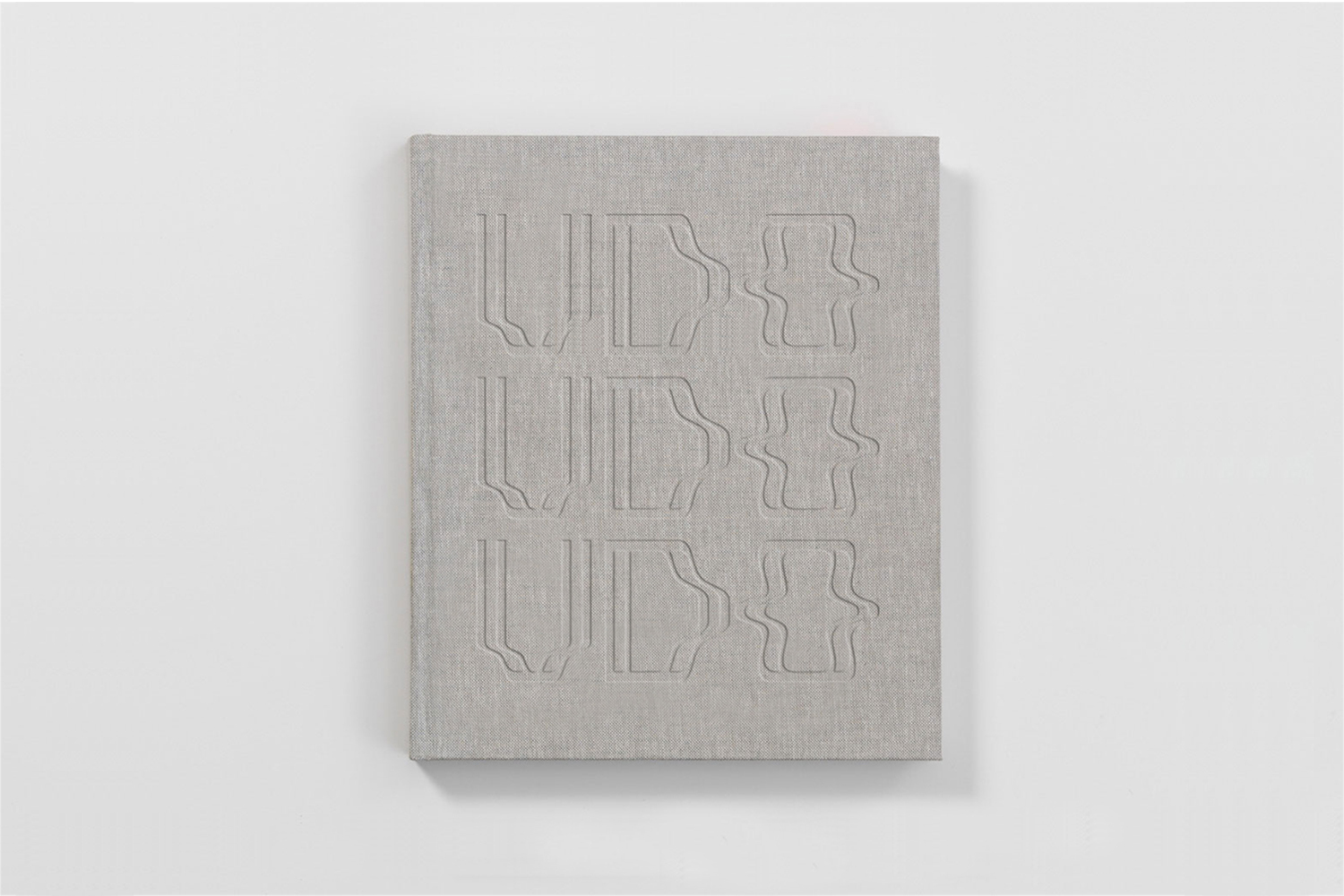 Grey linen-textured book with debossed typography on the cover against a plain white background