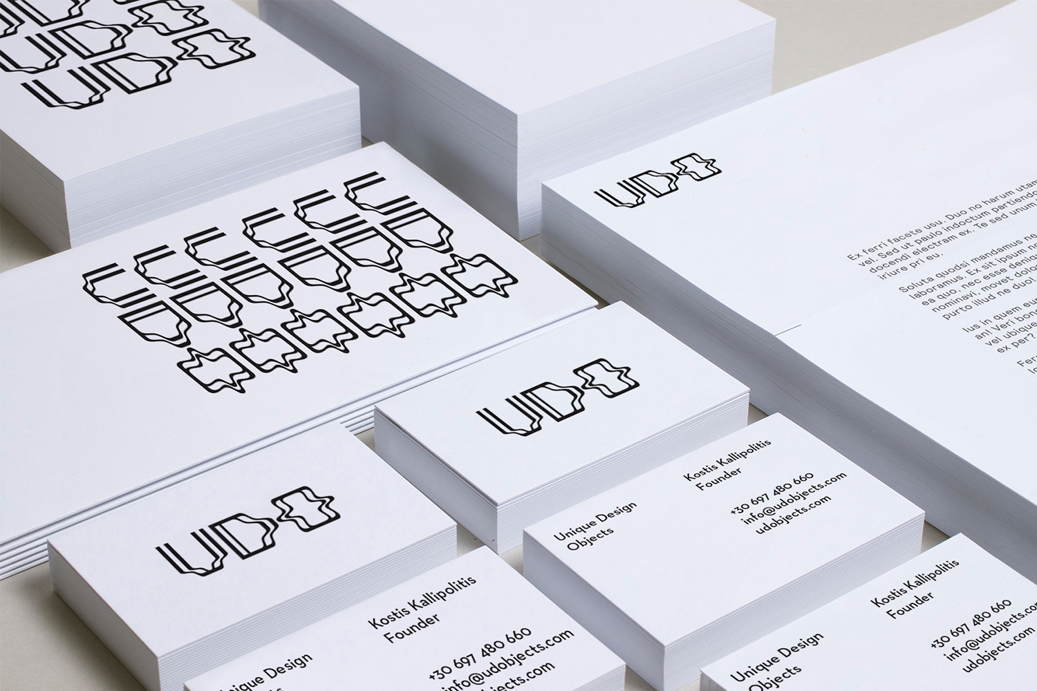 Stacks of white stationery and business cards featuring the UDO brand identity logo and typography.