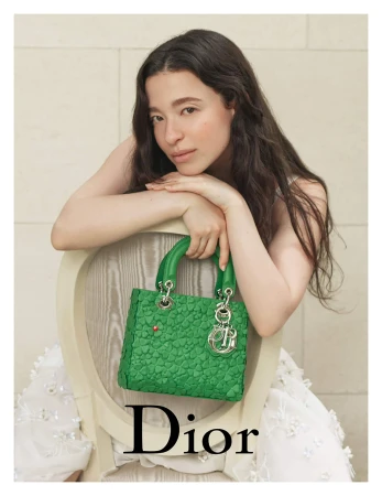 Mia Goth leaning on a chair holding a green Lady Dior handbag for the 2025 ad campaign