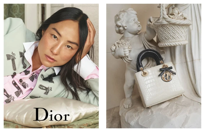 Greta Lee posing with a Lady Dior handbag next to a classical marble cherub statue for the 2025 campaign.