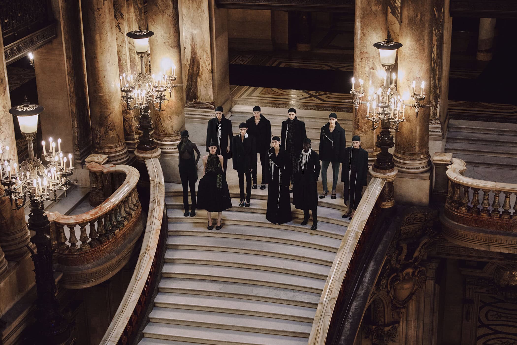 High-angle view of a group of models standing on grand marble staircase inside Palais Garnier for Dries Van Noten editorial project.