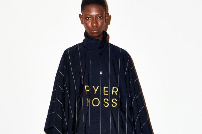 Model wearing a dark pinstripe top with gold lettering against a plain white background