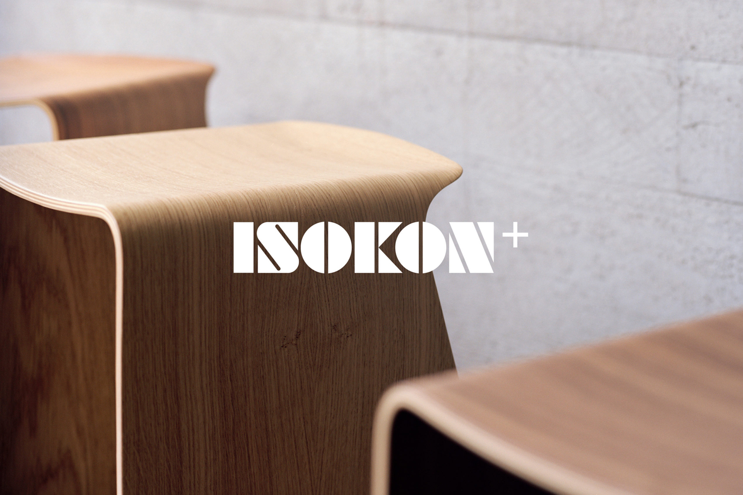 Wooden plywood stool featuring curved edges displayed against a textured concrete wall with white typography overlay