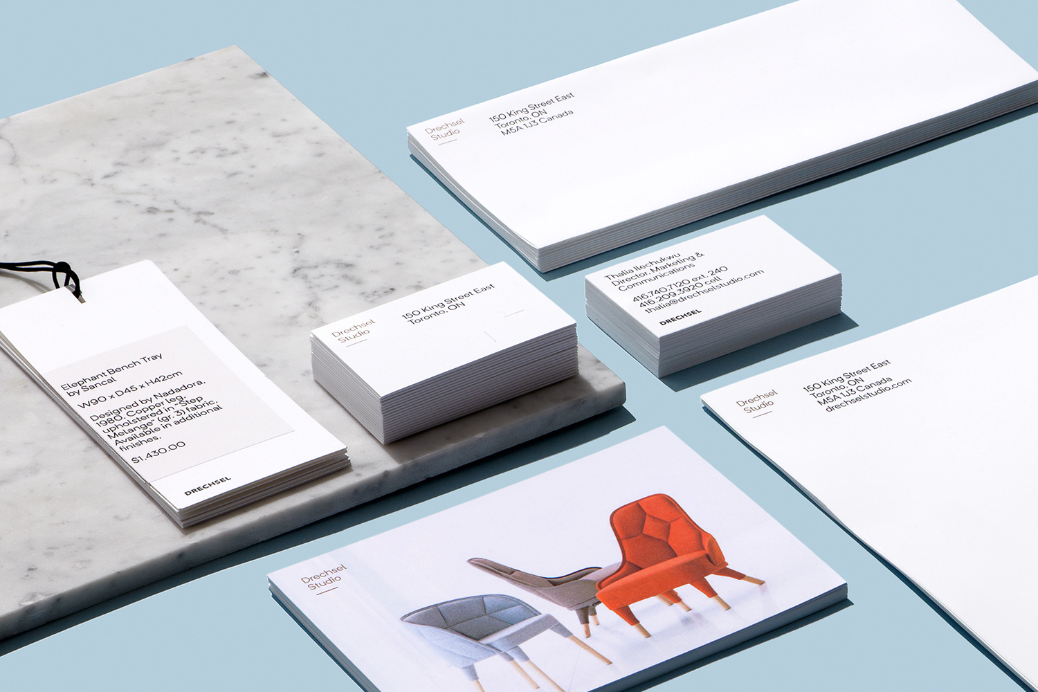 Branded stationery set for Drechsel by Underline Studio featuring business cards, envelopes, product tags, and a brochure on blue surface.
