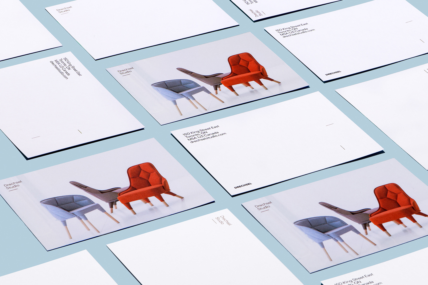 Multiple branded stationery cards and postcards arranged neatly on a light blue surface displaying modern armchairs.