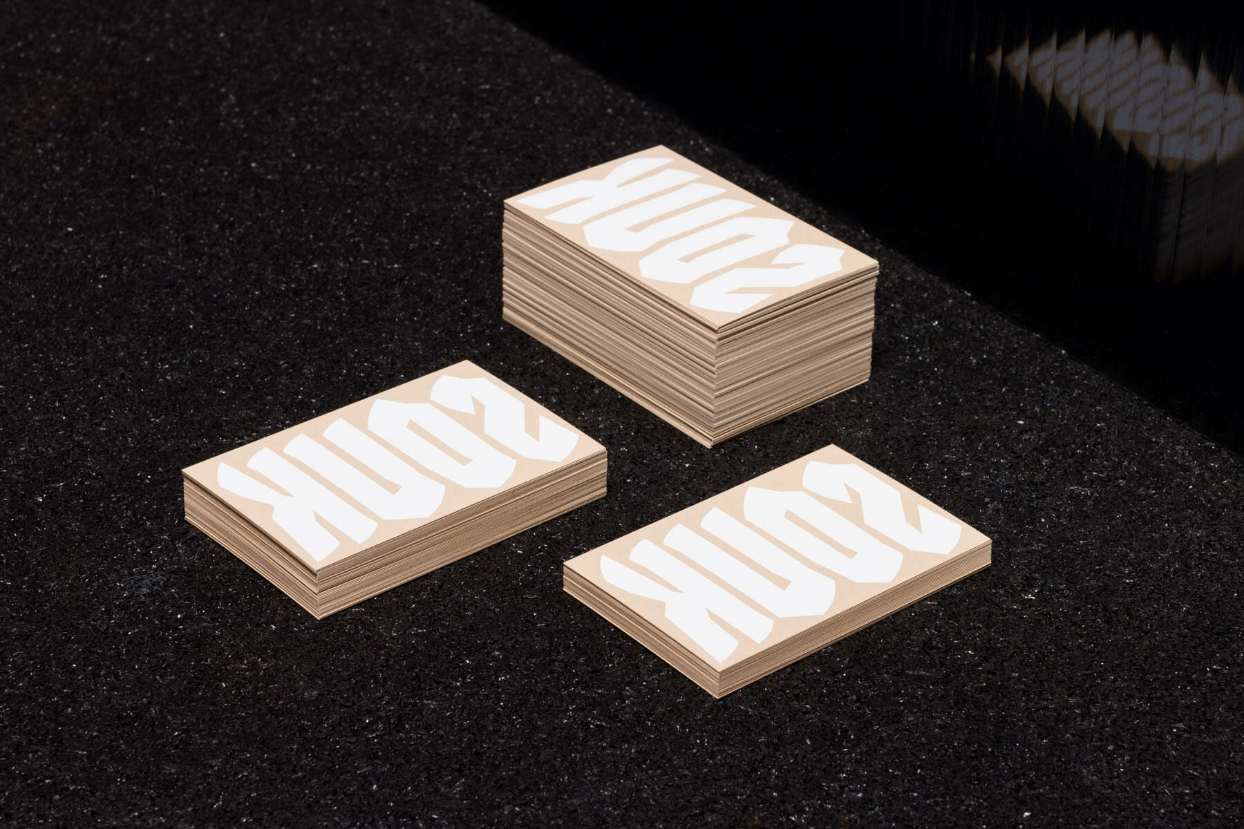 Stacks of light-colored business cards with bold white lettering set on a dark textured surface