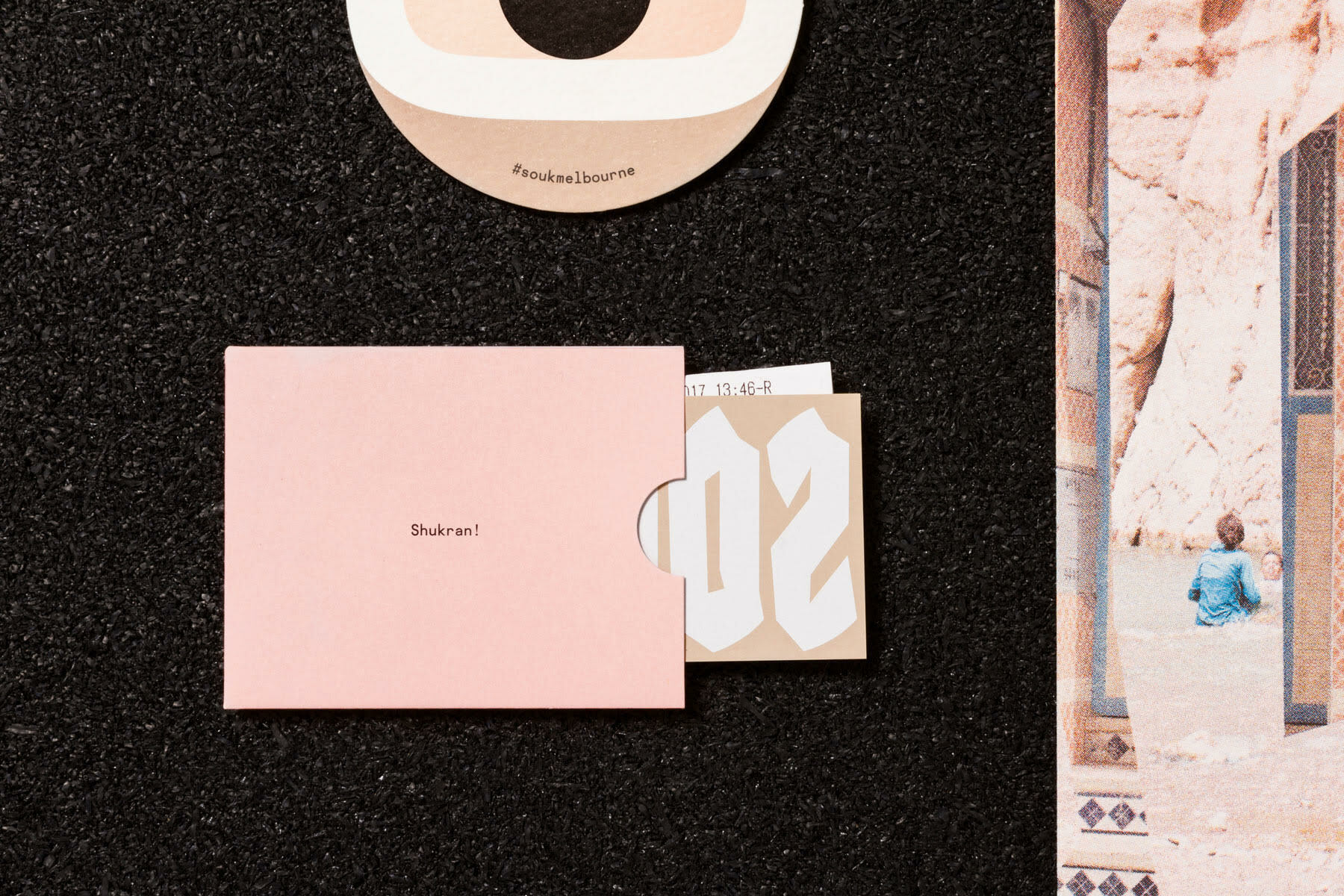 Graphic design brand identity items for Souk including pink sleeve and circular sticker on black surface